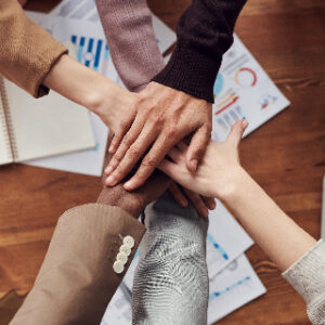 This image shows six hands going in the middle for a sort of all for one and one for all like a team.  This illustrates the important point that we cannot start a business all alone, we need guidance, support and mentorship.