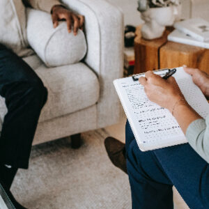 Image of a therapist taking notes (cannot see the faces), indicating my profession as a marriage and family therapist and the conflict I had about whether or not I would like to use a pseudonym.