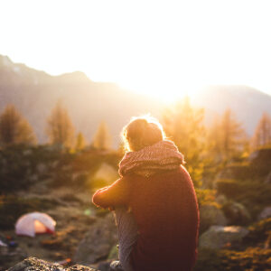 Image of a woman in nature sitting facing the warm sun upon her face looking peaceful that being her authentic self would be the answer to whether or not she should have a pseudonym.